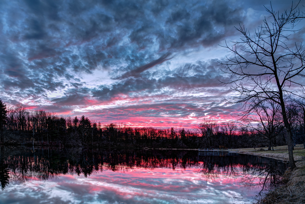 The setting sun paints the sky with vivid and dramatic colors that is reflected on a small Indiana pond.